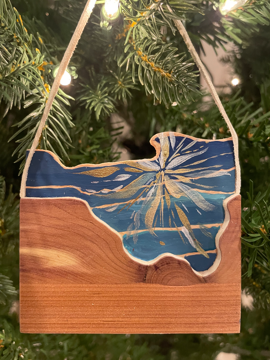 Wooden ornament with blue and gold design hanging on a Christmas tree.